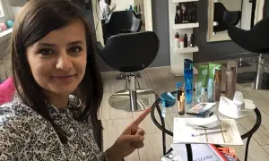 Kobieta w salonie kosmetycznym wskazuje na stolik z kosmetykami i katalogiem.