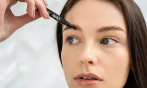 Kobieta aplikuje produkt do brwi za pomocą czarnego pisaka.
