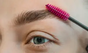 Zbliżenie na oko i brwi, na które nakładana jest szczoteczka do stylizacji.
