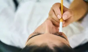 Stylistka rzęs aplikuje tusz. Zastanawiasz się, ile zarabia stylistka rzęs?