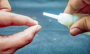 Dwie dłonie zbliżają się do siebie, jedna trzyma tubkę z super glue, druga jest gotowa do sklejenia.