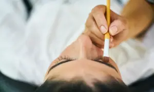 Zbliżenie na twarz kobiety, której brwi są koloryzowane pędzelkiem.