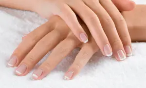 Dłonie z klasycznym french manicure. Delikatny róż i biel sprawiają, że palce wyglądają na dłuższe i smuklejsze. Jaki kolor paznokci wyszczupla palce? Ten subtelny french manicure!
