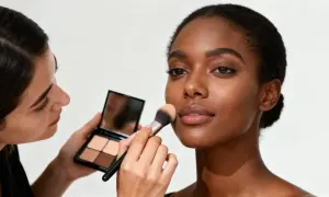 Profesjonalne szkolenia beauty: makijażystka aplikuje puder na twarz modelki.