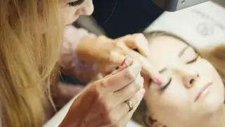 Podczas kursu stylizacji rzęs stylistka precyzyjnie pracuje nad przedłużeniem rzęs klientki.