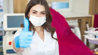 Profesjonalistka w masce i rękawiczkach pokazuje kciuk w górę. Idealne miejsce na kursy kosmetologia.