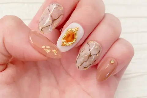 Eleganckie paznokcie z efektem marmuru i złotymi płatkami. Żel kamuflujący jak używać? Ten manicure pokazuje, jak pięknie można go połączyć z innymi zdobieniami.