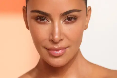 Zbliżenie na twarz Kim Kardashian z podkreślonymi rzęsami i błyszczącymi ustami.