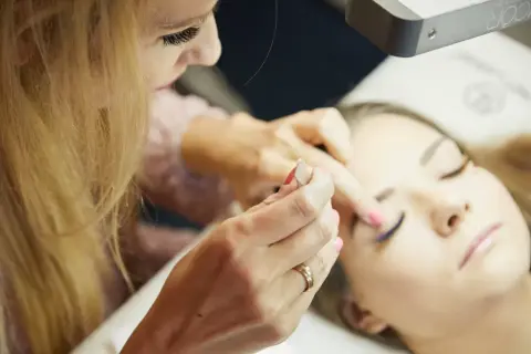 Profesjonalny kurs stylizacji rzęs: stylistka precyzyjnie dokłada rzęsy klientce, tworząc efektowny wachlarz.