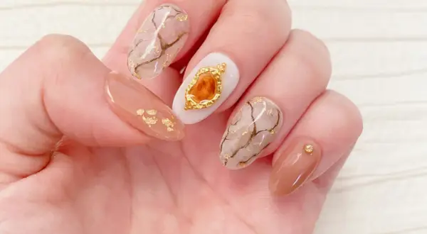 Eleganckie paznokcie z efektem marmuru i złotymi płatkami. Żel kamuflujący jak używać? Ten manicure pokazuje, jak pięknie można go połączyć z innymi zdobieniami.