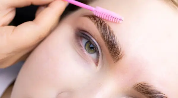 Styling perfectly laminated brows with a pink brush. Follow these zalecenia po laminacji brwi dla najlepszych efektów.