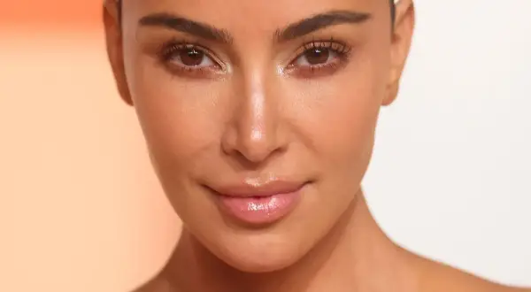 Zbliżenie na twarz Kim Kardashian z podkreślonymi rzęsami i błyszczącymi ustami.