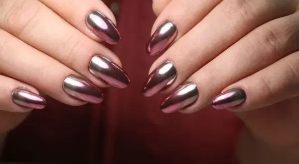 Dłonie z paznokciami w stylu lustrzane baby boomer. Kolorowy, metaliczny połysk odbija światło, tworząc efektowny manicure.