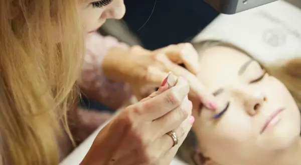 Profesjonalny kurs stylizacji rzęs: stylistka precyzyjnie dokłada rzęsy klientce, tworząc efektowny wachlarz.