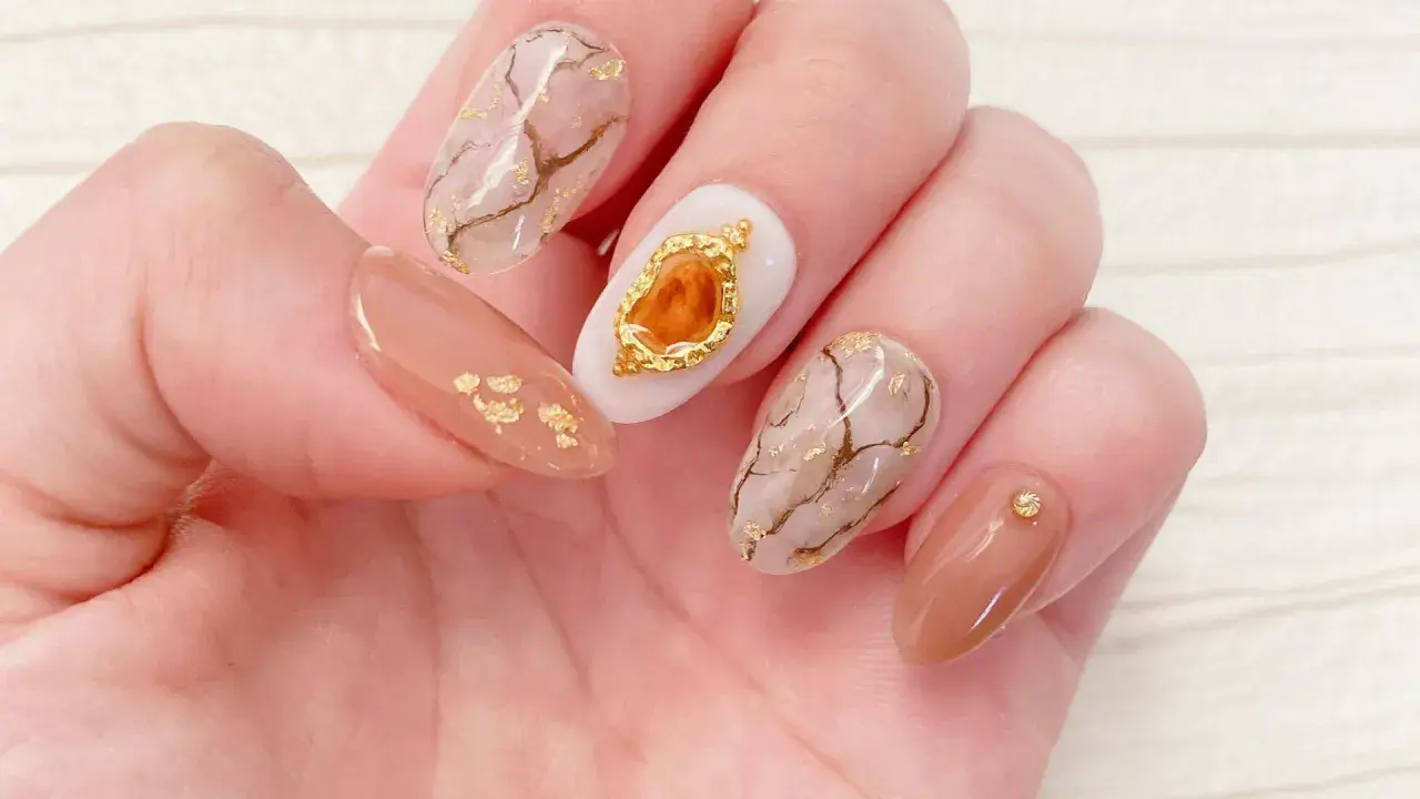 Eleganckie paznokcie z efektem marmuru i złotymi płatkami. Żel kamuflujący jak używać? Ten manicure pokazuje, jak pięknie można go połączyć z innymi zdobieniami.