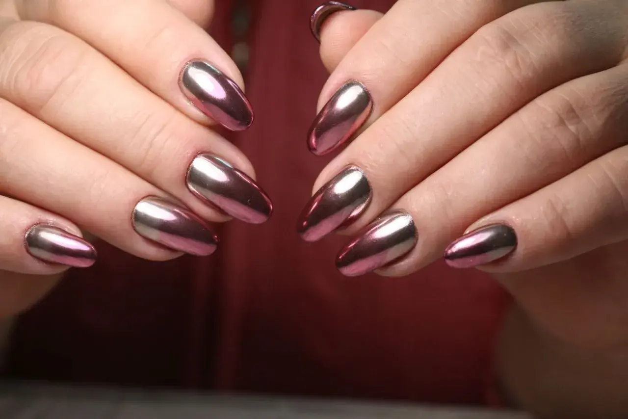 Dłonie z paznokciami w stylu lustrzane baby boomer. Kolorowy, metaliczny połysk odbija światło, tworząc efektowny manicure.