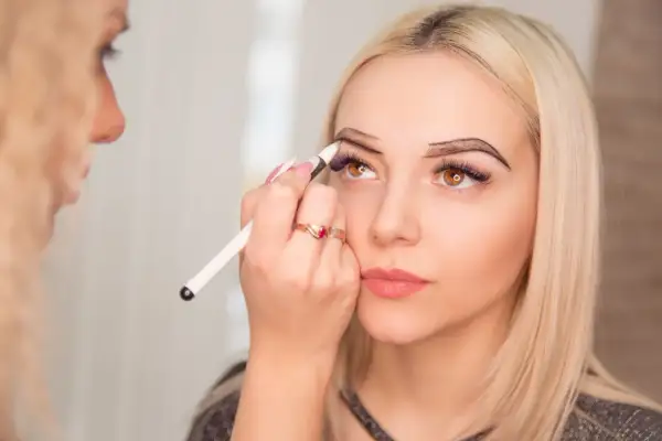 Stylistka brwi precyzyjnie rysuje kontur na łuku brwiowym klientki.