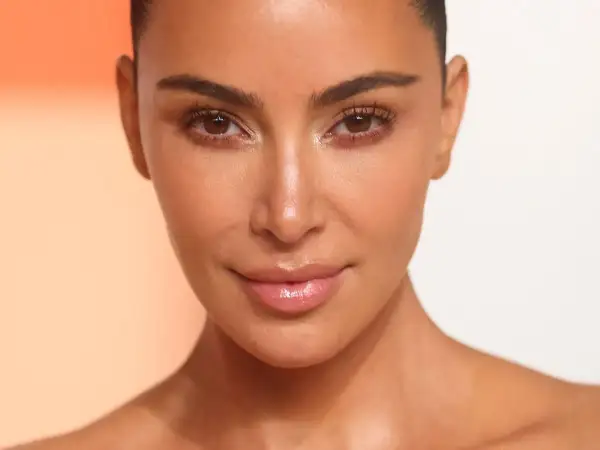 Zbliżenie na twarz Kim Kardashian z podkreślonymi rzęsami i błyszczącymi ustami.