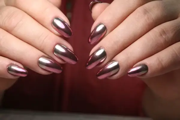 Dłonie z paznokciami w stylu lustrzane baby boomer. Kolorowy, metaliczny połysk odbija światło, tworząc efektowny manicure.
